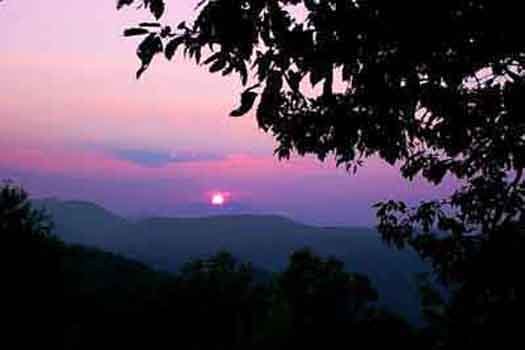 a sun setting behind the smoky mountains at america's view a 2 bedroom cabin rental located in pigeon forge