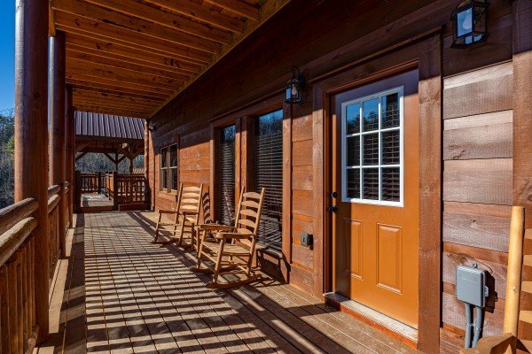 Deck rocking chairs and entrance at Mountain Joy, an 8 bedroom cabin rental located in Pigeon Forge