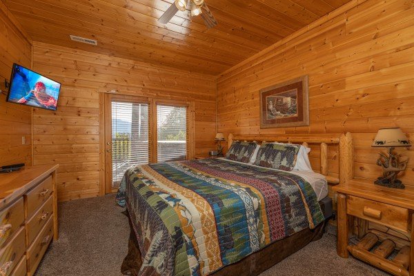 Bedroom with a dresser, TV, and deck access at Grizzly's Den, a 5 bedroom cabin rental located in Gatlinburg