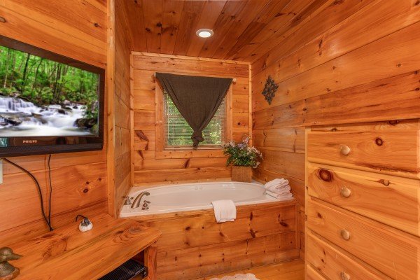 Bedroom with a TV, dresser, and in room jacuzzi at Swept Away in the Smokies, a 1 bedroom cabin rental located in Pigeon Forge
