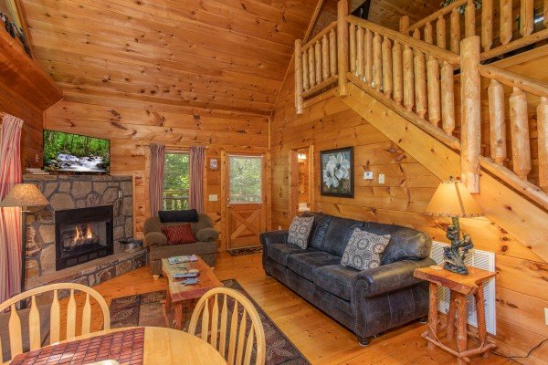 Living room with fireplace, TV, sofa, and chair at Swept Away in the Smokies, a 1 bedroom cabin rental located in Pigeon Forge