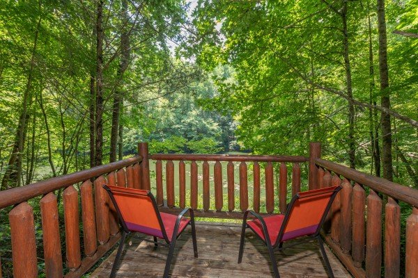Two chairs on the lower deck overlooking the stream at Swept Away in the Smokies, a 1 bedroom cabin rental located in Pigeon Forge