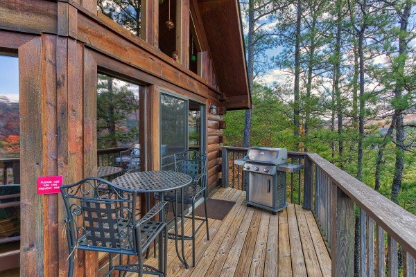 Gas grill and dining space for two on the deck at R & R Hideaway, a 1 bedroom cabin rental located in Pigeon Forge
