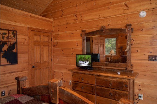 Bedroom with a dresser and mirror and a television at Cedar Creeks, a 2-bedroom cabin rental located near Douglas Lake