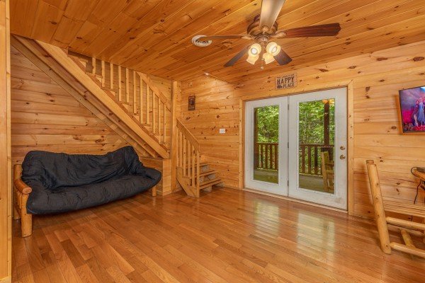 Futon and deck access in the lower living room at Bootlegger Hill Hideaway, a 2 bedroom cabin rental located in Pigeon Forge