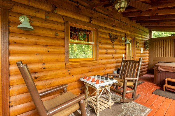 Screened porch with rocking chairs, checkers, and a hot tub at Fowl Play, a 1 bedroom cabin rental located in Pigeon Forge
