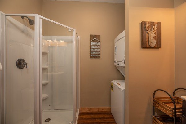 Stacked washer and dryer next to a shower stall in a bathroom at Hawk’s Heart Lodge, a 3 bedroom cabin rental located in Pigeon Forge