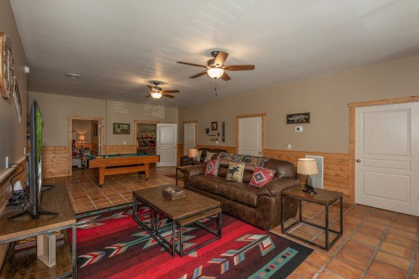 Sofa and TV in a living room with a pool table at Hawk’s Heart Lodge, a 3 bedroom cabin rental located in Pigeon Forge