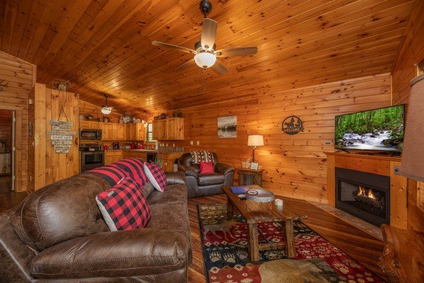 Living room with fireplace and TV next to the open kitchen at Hawk’s Heart Lodge, a 3 bedroom cabin rental located in Pigeon Forge