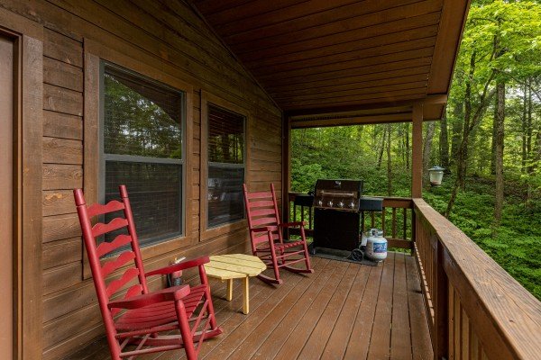 Rocking chairs and a grill on a covered porch at Hawk’s Heart Lodge, a 3 bedroom cabin rental located in Pigeon Forge