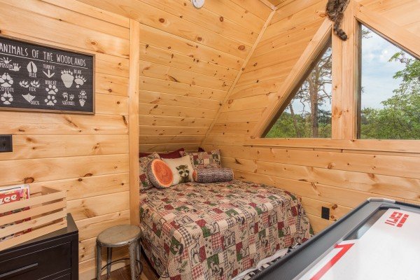 Loft space with a queen bed and air hockey table at Gatlinburg Treehouse, a 1-bedroom cabin rental located in Gatlinburg
