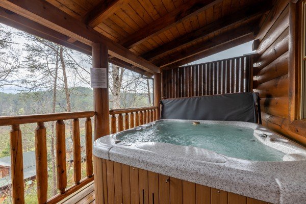 Hot tub on a covered deck at Absolutely Wonderful, a 2 bedroom cabin rental located in Pigeon Forge