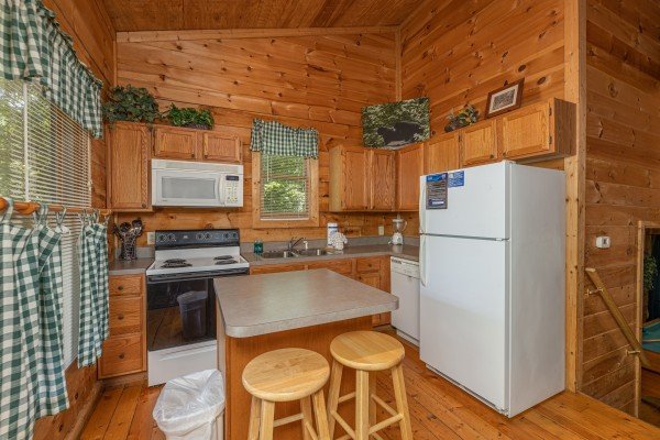 Kitchen with white appliances and island seating for two at Moonlight in the Boondocks, a 2 bedroom cabin rental located in Gatlinburg