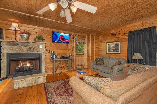 Living room with a fireplace, TV, and two loveseats at Moonlight in the Boondocks, a 2 bedroom cabin rental located in Gatlinburg