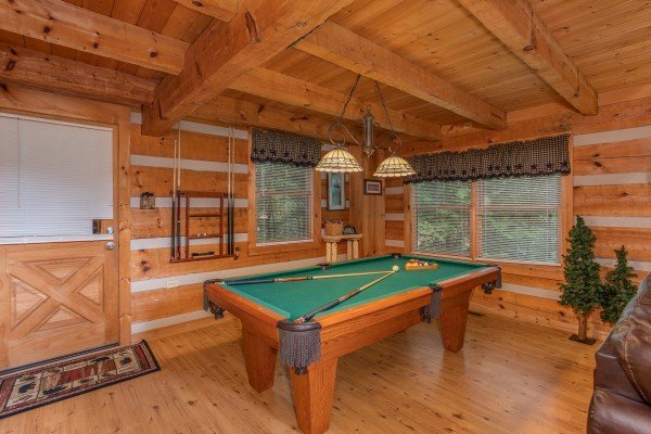 Green felted pool table in the living room at Bearfoot Crossing, a 1-bedroom cabin rental located in Pigeon Forge