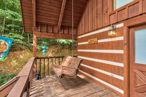 Porch swing on a covered deck at Bearfoot Crossing, a 1-bedroom cabin rental located in Pigeon Forge