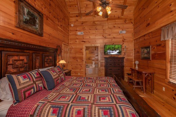 Bedroom with a king-sized bed, dresser, writing desk, and television at Bearfoot Paradise, a 3-bedroom cabin rental located in Pigeon Forge
