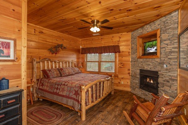 Bedroom on the lower level with a king log bed, fireplace, and TV at Bearfoot Paradise, a 3 bedroom cabin rental in Pigeon Forge
