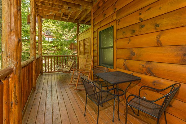 Deck with a bistro set for three, porch swing and rocking chair at Bearfoot Paradise, a 3-bedroom cabin rental located in Pigeon Forge
