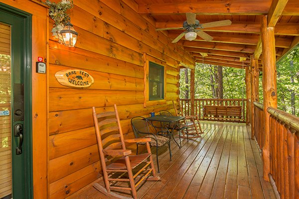 Front deck with rockers and bistro set at Bearfoot Paradise, a 3-bedroom cabin rental located in Pigeon Forge