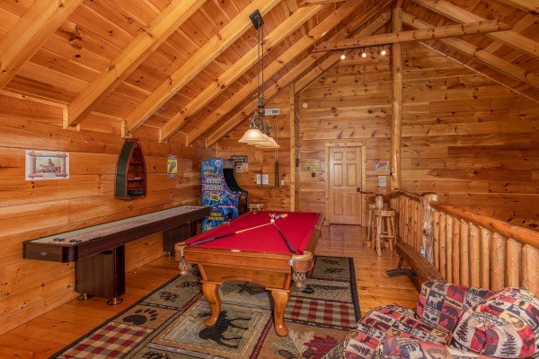Red felted pool table, shuffleboard game, and arcade game in the game loft at Bearfoot Paradise, a 3-bedroom cabin rental located in Pigeon Forge