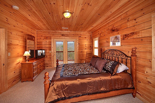 King sized bed in main level bedroom with patio doors to deck at Highlander, a 4 bedroom cabin rental located in Gatlinburg