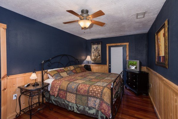 Dark blue room with a king-sized bed, television, and dresser at Breezy Mountain Lodge, an 11-bedroom cabin rental located in Pigeon Forge