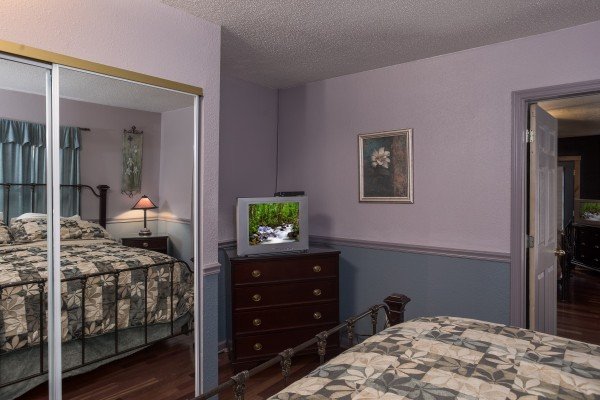 Purple bedroom with a flat-screen TV, dresser, and mirrored closet doors at Breezy Mountain Lodge, an 11-bedroom cabin rental located in Pigeon Forge