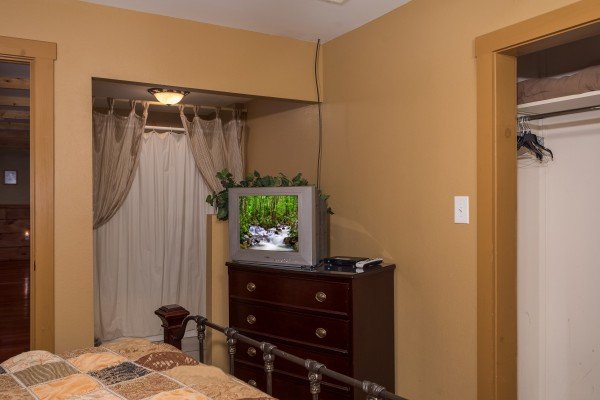 Tan bedroom with ensuite bath, television, and dresser at Breezy Mountain Lodge, an 11-bedroom cabin rental located in Pigeon Forge