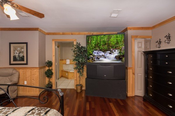Bedroom with a large theater-sized television at Breezy Mountain Lodge, an 11-bedroom cabin rental located in Pigeon Forge