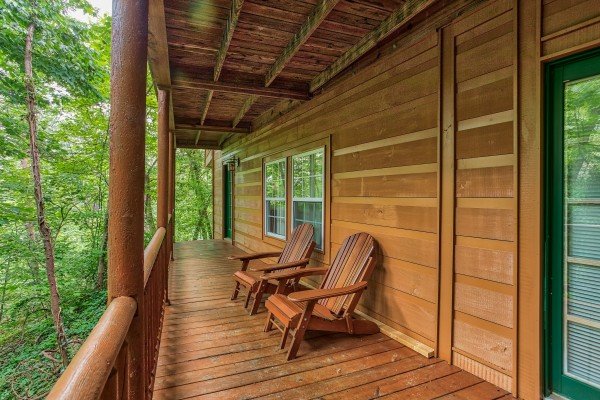 Two Adirondack chairs on a covered deck at Breezy Mountain Lodge, an 11-bedroom cabin rental located in Pigeon Forge