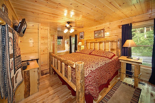 King sized bed with night stands and flat screen tv above a chest of drawers at Brownie Bear, a 1-bedroom cabin rental located in Gatlinburg