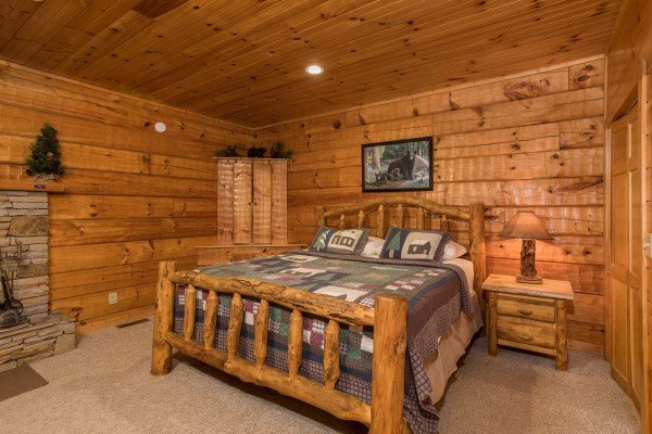 Log bed with night stand and lamp at Mountain Magic, a 1 bedroom cabin rental located in Pigeon Forge