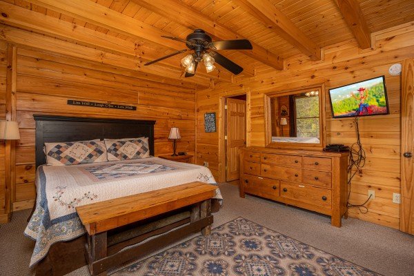 Master bedroom with bench and flat screen at Rocky Top Memories, a 2 bedroom cabin rental located in Pigeon Forge