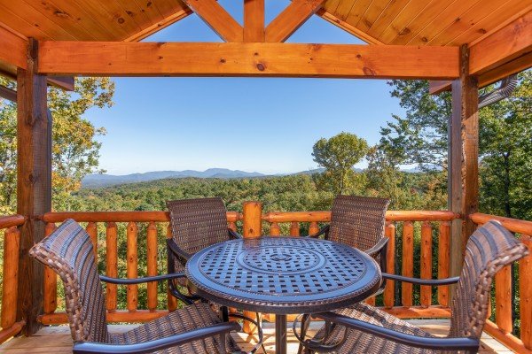 Dining table for four on the covered deck at Panorama, a 2 bedroom cabin rental located in Pigeon Forge