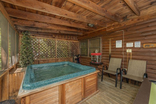 Hot tub on a screened porch at Whispering Pines, a 2 bedroom cabin rental located in Pigeon Forge