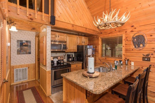 Breakfast bar for three and kitchen with stainless appliances at Whispering Pines, a 2 bedroom cabin rental located in Pigeon Forge