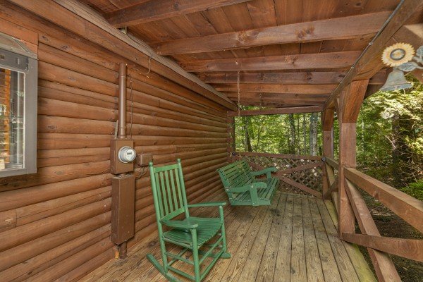 Rocking chair and swing on a covered deck at Whispering Pines, a 2 bedroom cabin rental located in Pigeon Forge