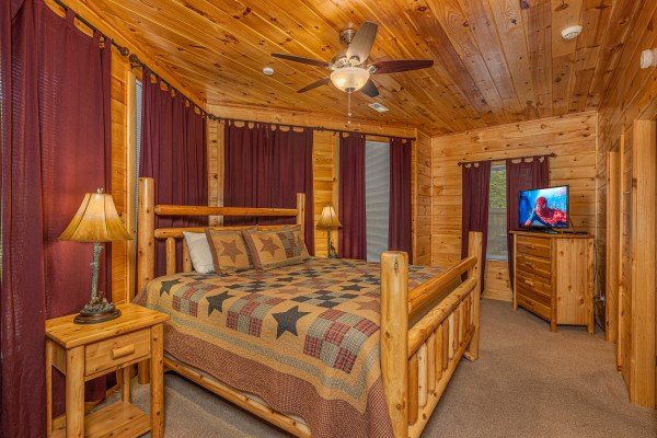 King log bed, dresser, and TV in a bedroom at Smokies Paradise Lodge, a 5 bedroom cabin rental located in Pigeon Forge