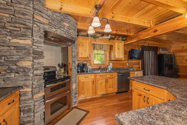 Kitchen with stainless appliances and custom stone work at Smokies Paradise Lodge, a 5 bedroom cabin rental located in Pigeon Forge