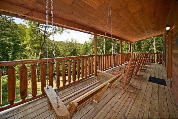 Covered porch with a swing and rocking chairs at Just Relax, a 2 bedroom cabin rental located in Pigeon Forge