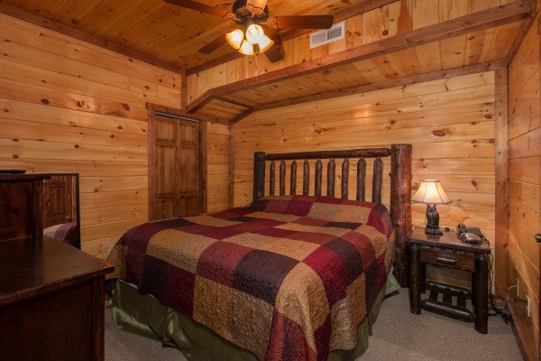 Bedroom with a log bed, night stand, and lamp at Tennessee Treasure, a 3 bedroom cabin rental located in Pigeon Forge
