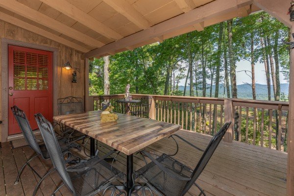 Dining for six on a covered porch at Bearfoot Adventure, a 2 bedroom cabin rental located in Gatlinburg