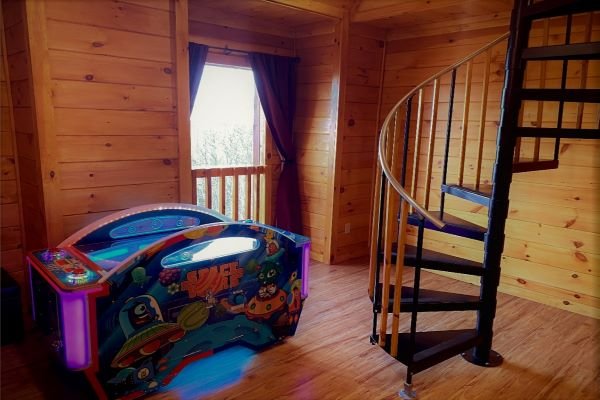 Arcade and spiraling staircase at Eagle's Sunrise, a 2 bedroom cabin rental located in Pigeon Forge