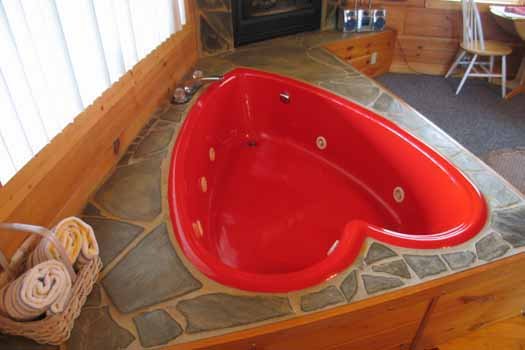 Red heart shaped jacuzzi tub at Love Me Tender, a 1 bedroom cabin rental located in Pigeon Forge
