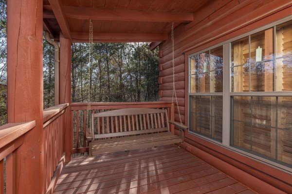 Porch swing on a covered deck at Wilderness Adventure, a 2 bedroom cabin rental in Pigeon Forge