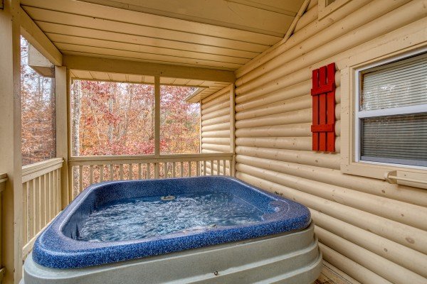 Hot tub on a screened in, covered porch with a wooded view at Bearly in the Mountains, a 5-bedroom cabin rental located in Pigeon Forge