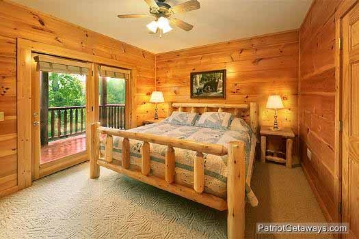 King bed on log frame with patio door to deck in bedroom at Flying with Eagles, a 3-bedroom cabin rental located in Pigeon Forge