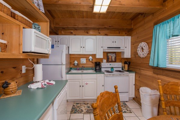Kitchen with white cabinets and white appliances at Living on Love, a 2 bedroom cabin rental located in Pigeon Forge