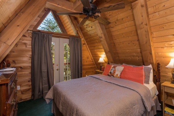 Bedroom with night stands, lamps, and deck access at Living on Love, a 2 bedroom cabin rental located in Pigeon Forge